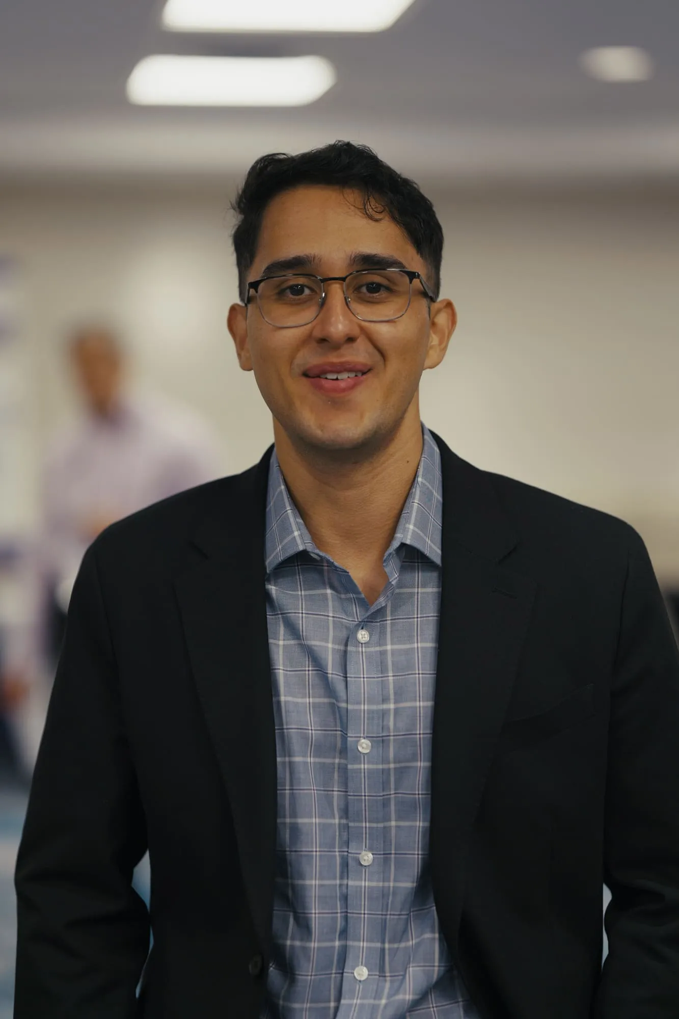Professional event portrait of a man wearing glasses and a dark blazer