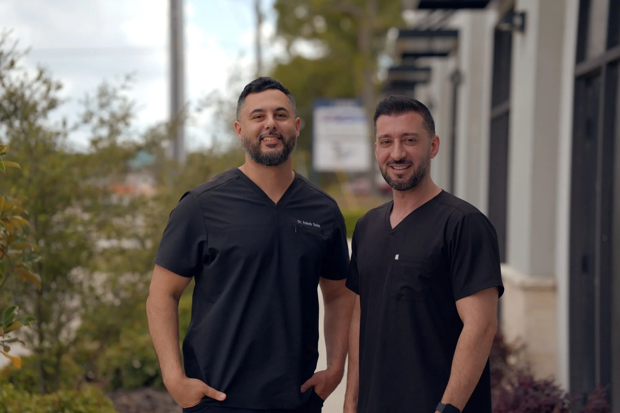 Outdoor portrait of two doctors wearing black medical scrubs