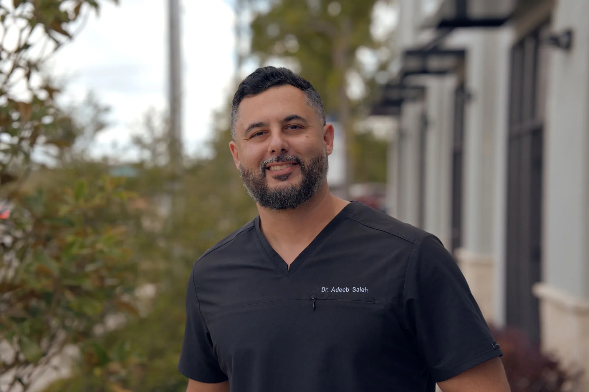 Close outdoor professional portrait of a doctor wearing black medical scrubs