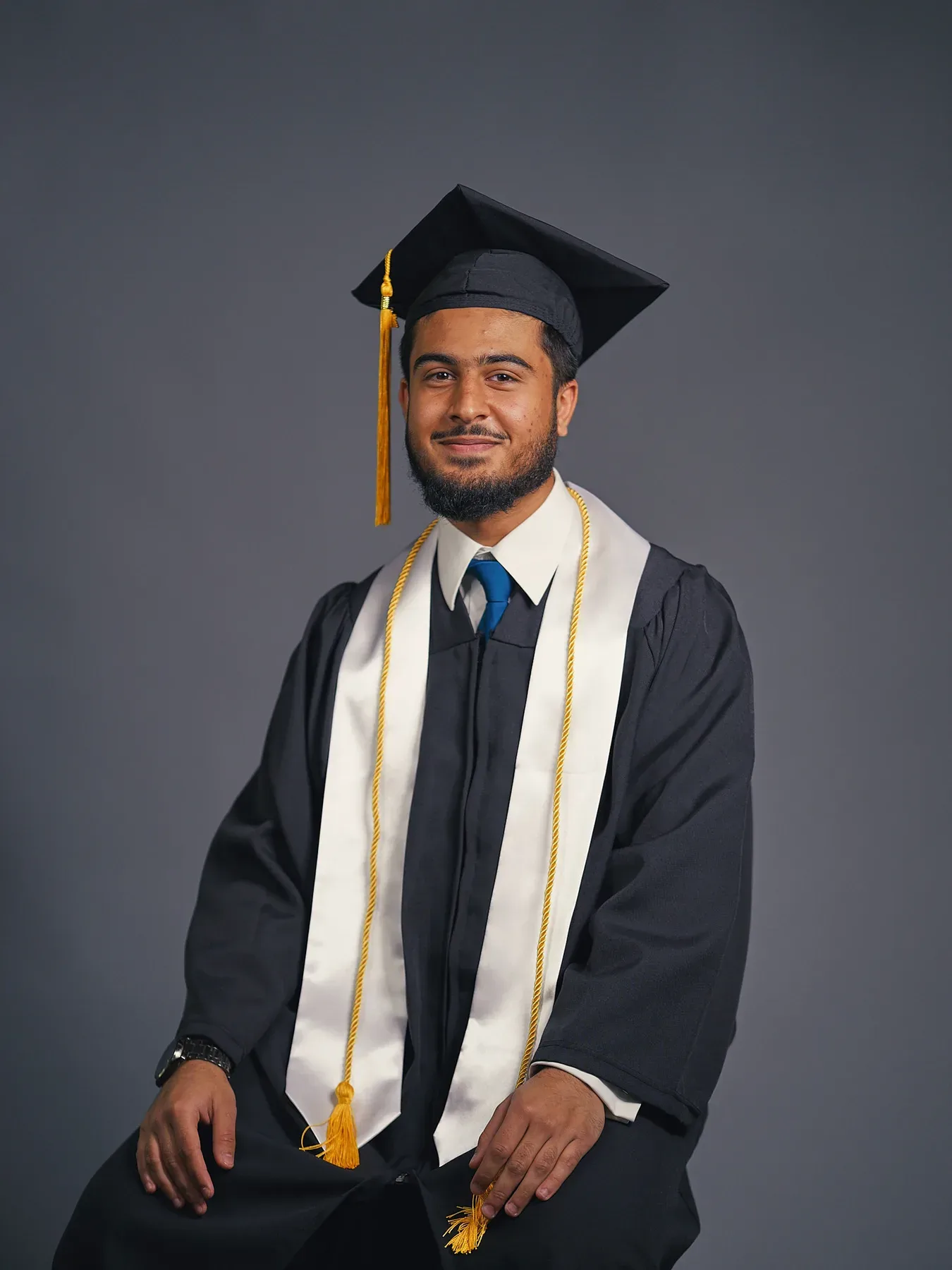 Bayaan Academy graduate wearing a navy cap and gown with a gold stole