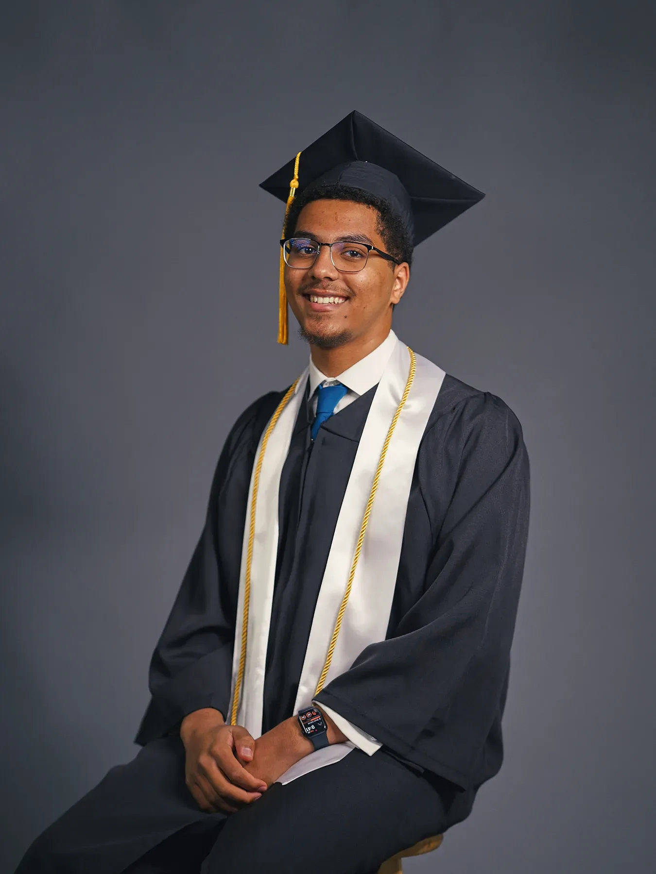 Bayaan Academy graduate wearing a navy cap and gown with a white stole