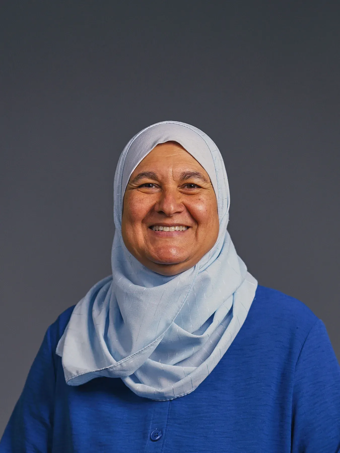 Bayaan Academy staff member smiling in a light blue hijab